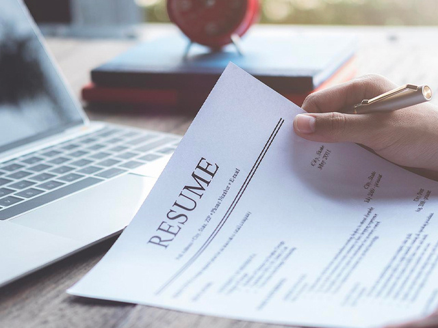 Hand Holding Resume and Pen