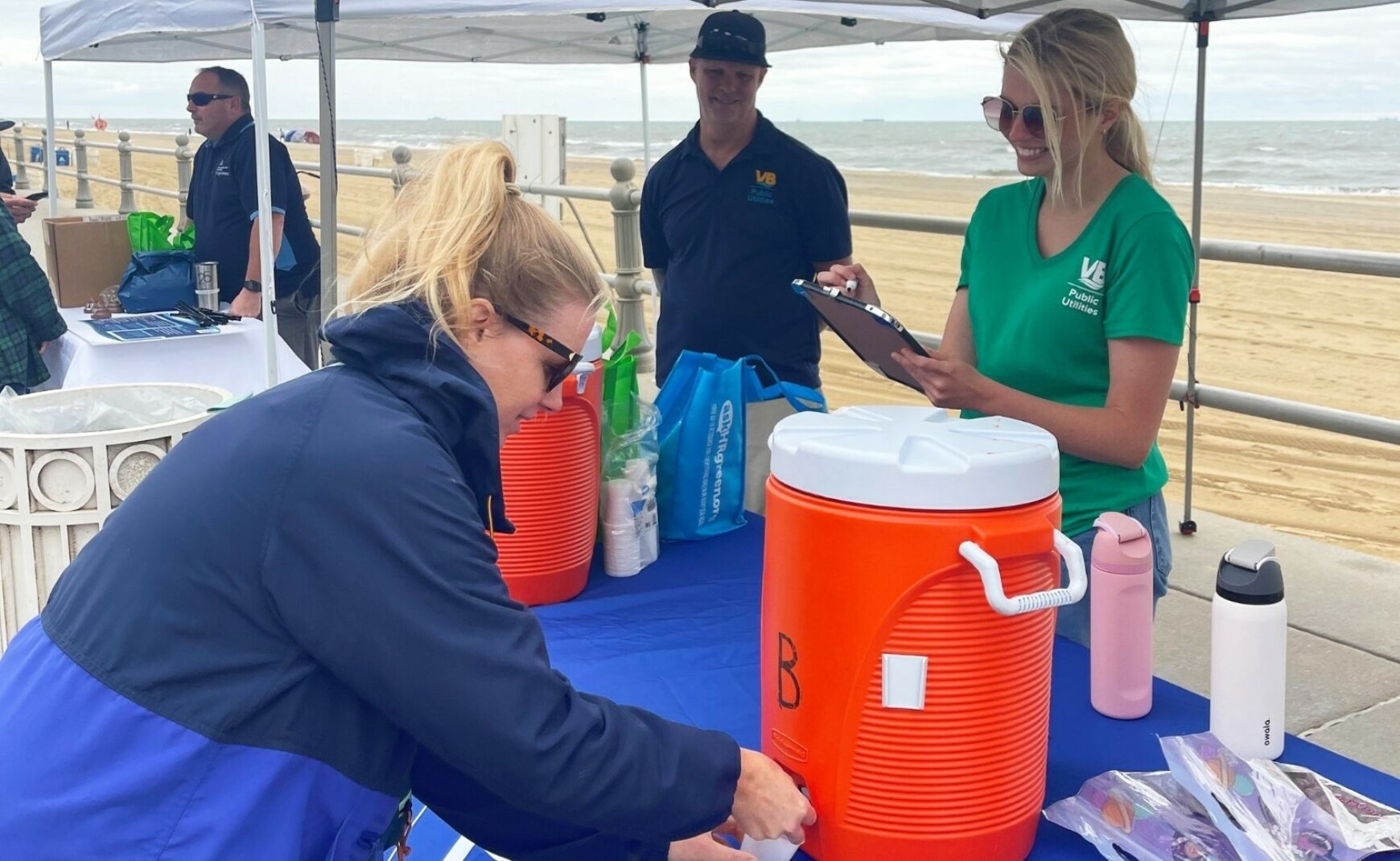 Person filling a paper small cup from a cooler of water