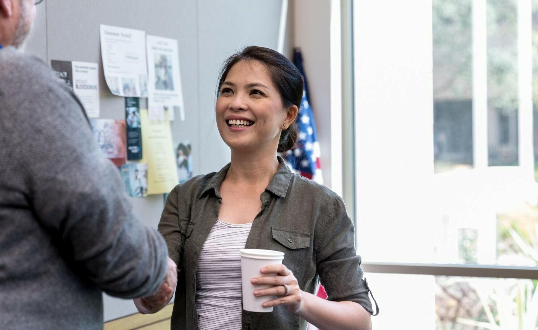 Woman holding cup smiling and shaking hands
