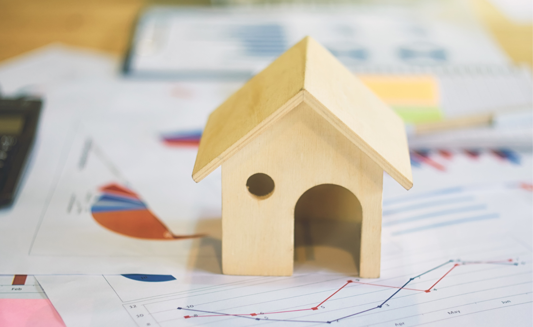 Wooden House on top of charts and graphs