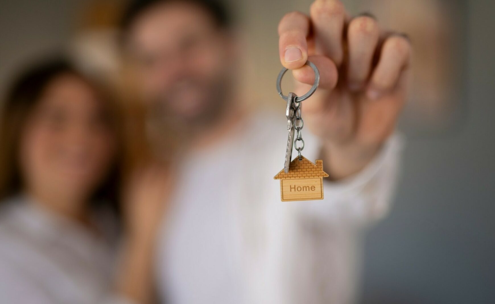 Couple holding key with keychain of a home