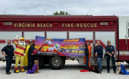 Firefighters and dogs in front of fire truck holding fire prevention week banner