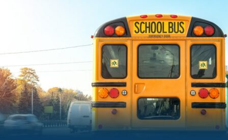View of back of school bus with cards driving by