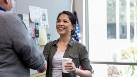 Woman holding cup smiling and shaking hands