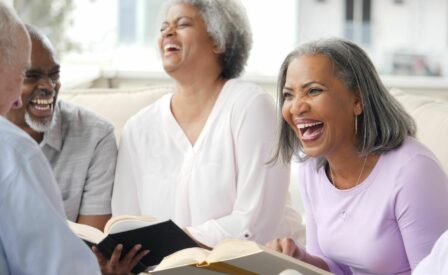 Older group of people laughing and smiling while holding books