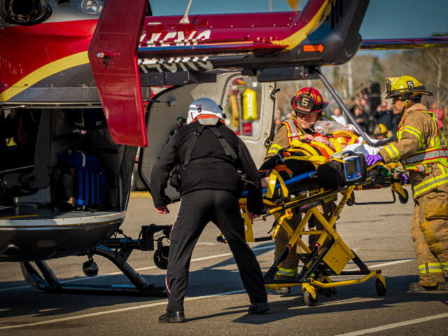 Firefighters loading patient on stretcher into helocopter