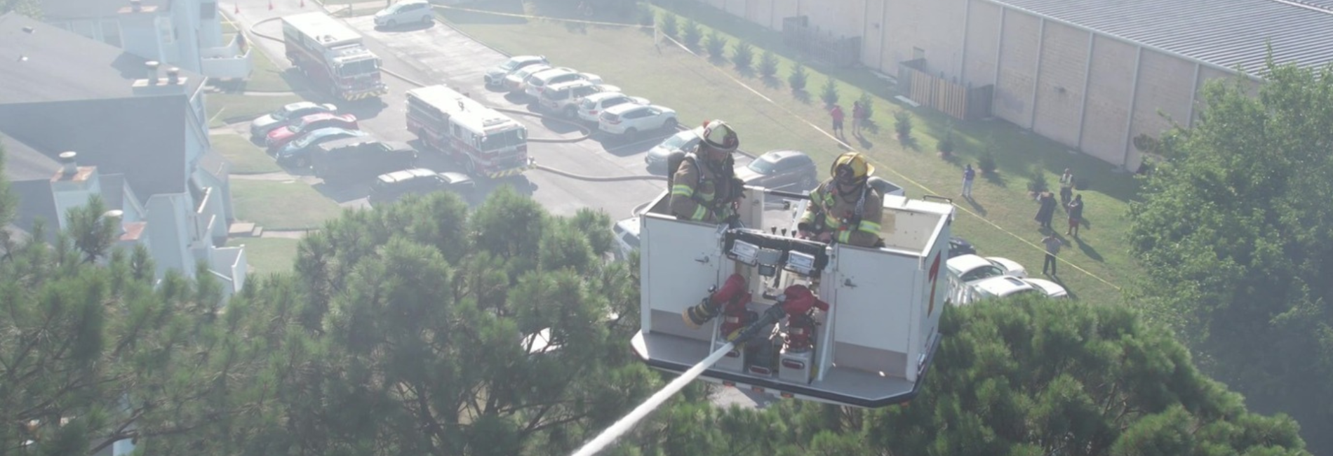 Two firefighters in bucket ladder with hose