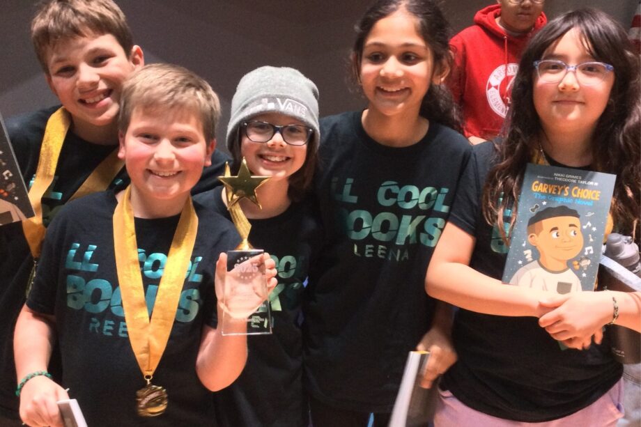 Kids in black shirts proudly displaying their medals