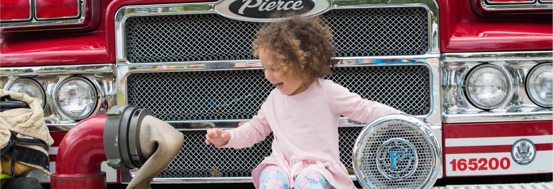 Young child sitting on fire truck bumper