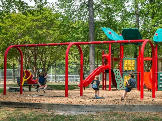 City view park children playing on a red swing set at the city view park playground