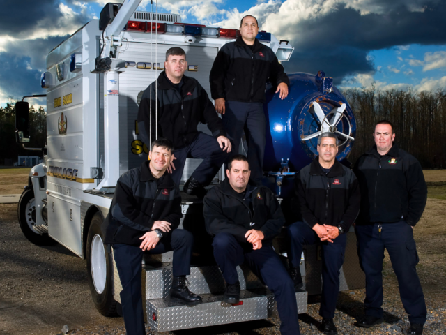 Bomb squad members posed on back of bomb disposal vehicle