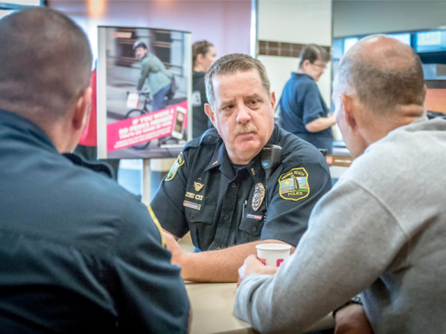 Police officer listens to two residents at Coffee With a Cop event