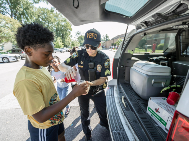 Police officer pouring water for young boy at community event