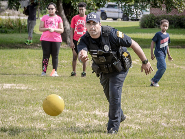 Police officer rolling a kickball at school event