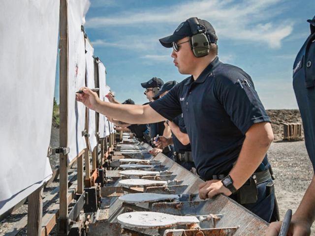 Police recruits checking target sheets at shooting range