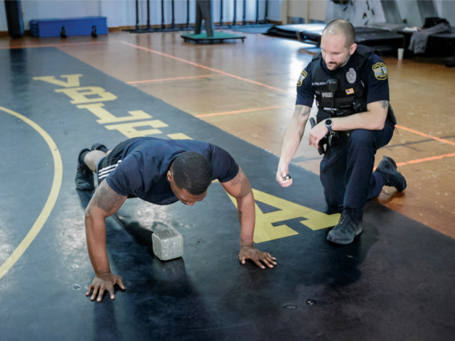 Recruit doing pushups and being monitored by training officer
