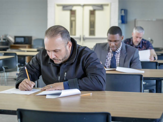 Recruits taking test at police academy in classroom