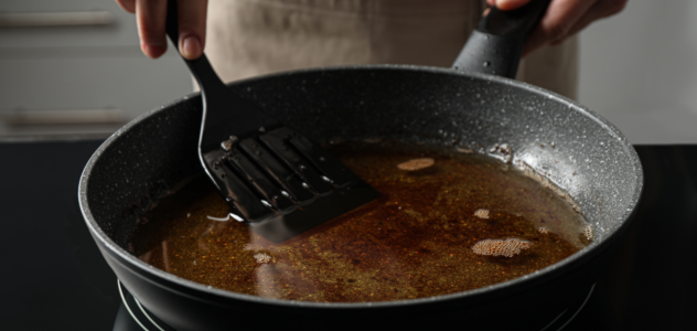 Cooking pan with used oil sitting on flattop stove