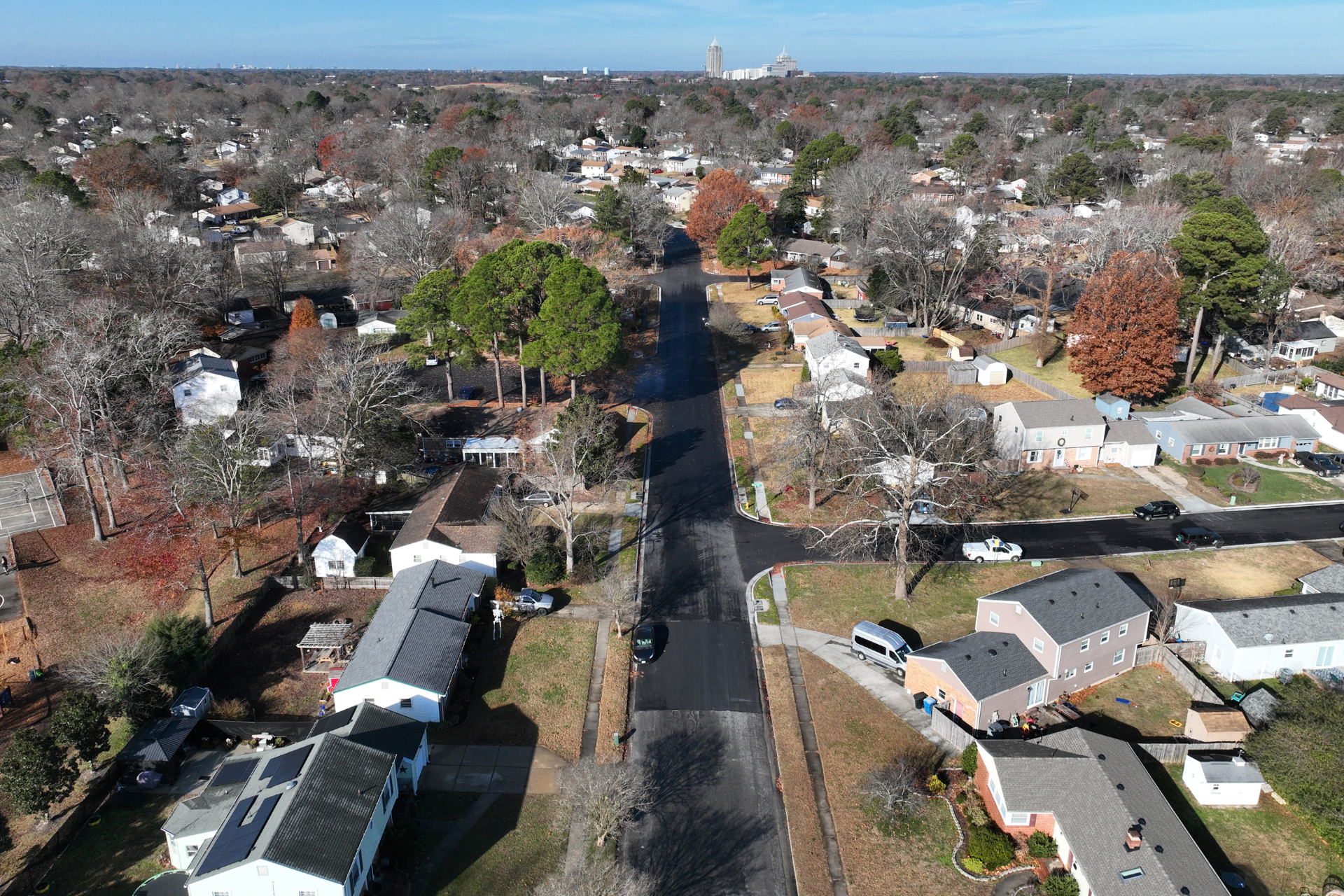 From aerial perspective, residential houses, lawns, vehicles, and trees and various connecting streets: Old Forge Court (right-foreground), Plaza Trail Circle (left-middle), South Kings Forks Road (mid-background), and continuing to Red Lion Road (right-background) against a mostly sunny sky.