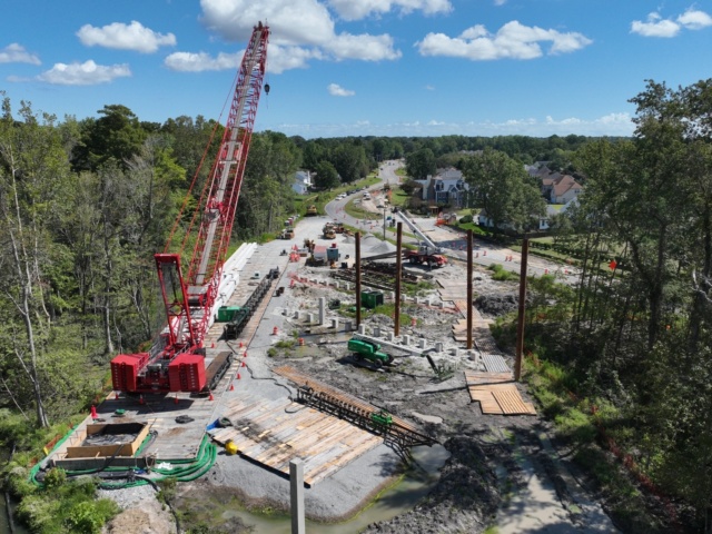 Aerial view of Elbow Road project with red crane in place to begin piledriving operations for the new bridge